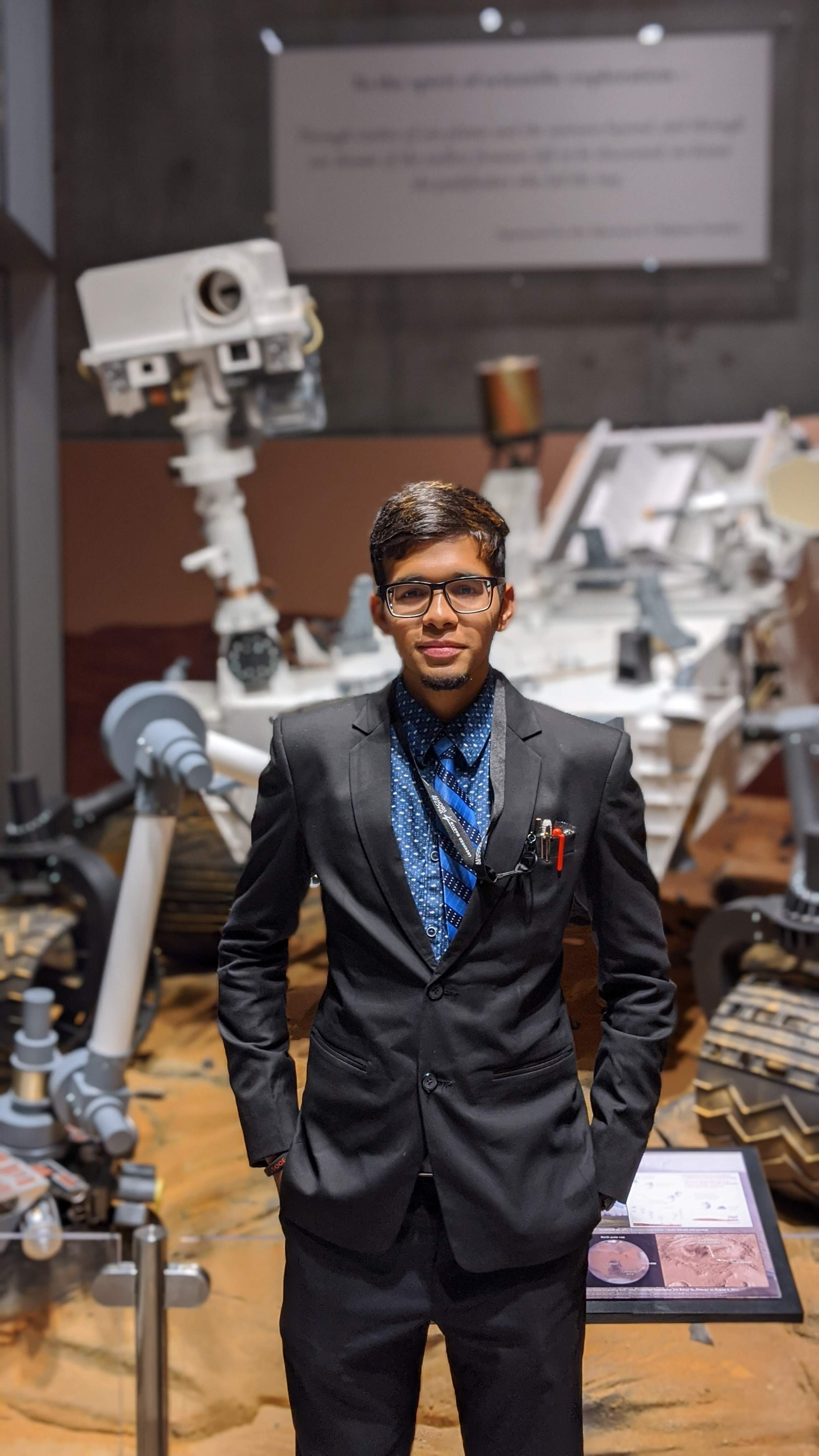 Arsh Nadkarni stands in front of rover model