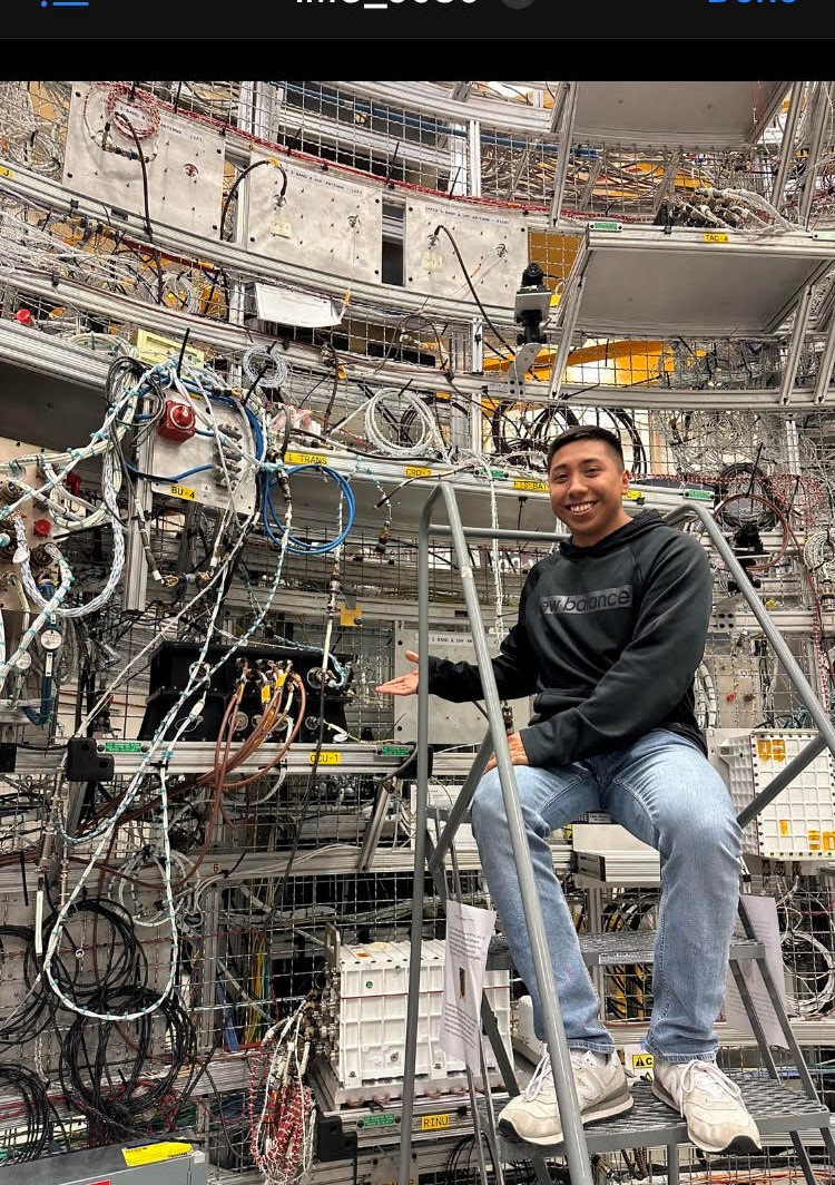 David Ordaz Perez in the lab at Marshall Spaceflight Center. David stands on a latter next to all of the lab equipment.