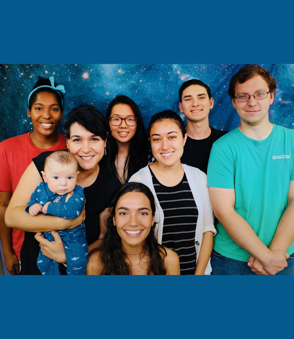 Cathryn Sephus, top left, and Betul Kacar, second from left, pose with members of the Kacar Lab. Betul Kacar holds her child.