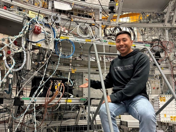 David Ordaz Perez in the lab at Marshall Spaceflight Center. David stands on a latter next to all of the lab equipment.