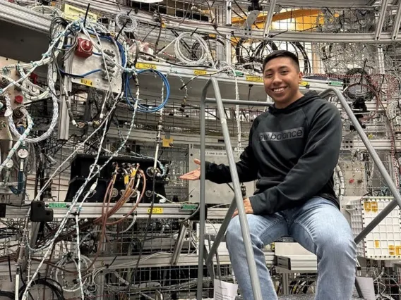 David Ordaz Perez in the lab at Marshall Spaceflight Center. David stands on a latter next to all of the lab equipment.