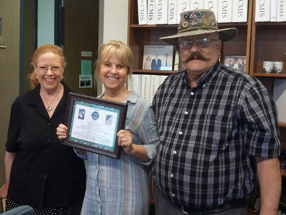 Susan Brew holds award certificate with Dolores and Rick Hill