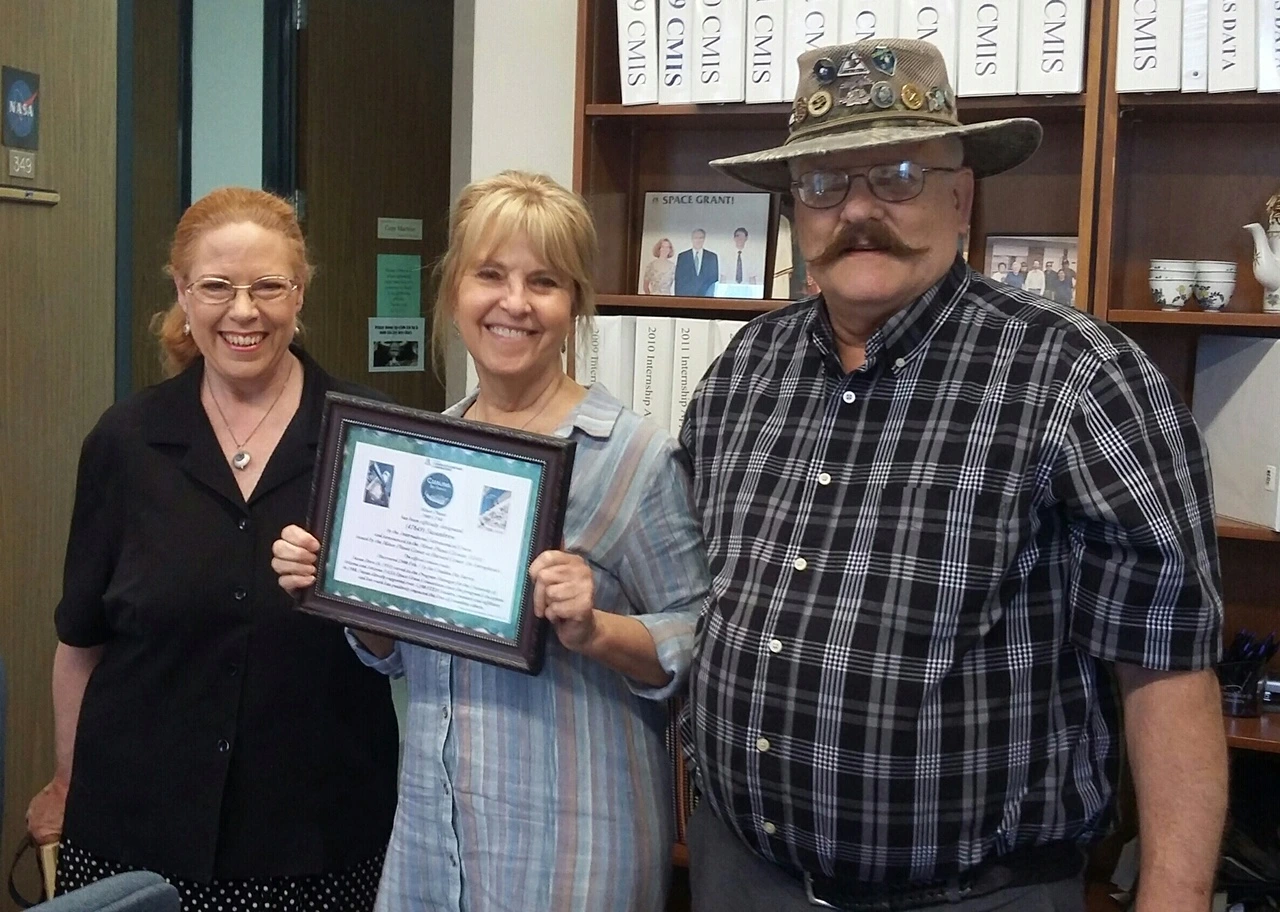 Susan Brew holds award certificate with Dolores and Rick Hill